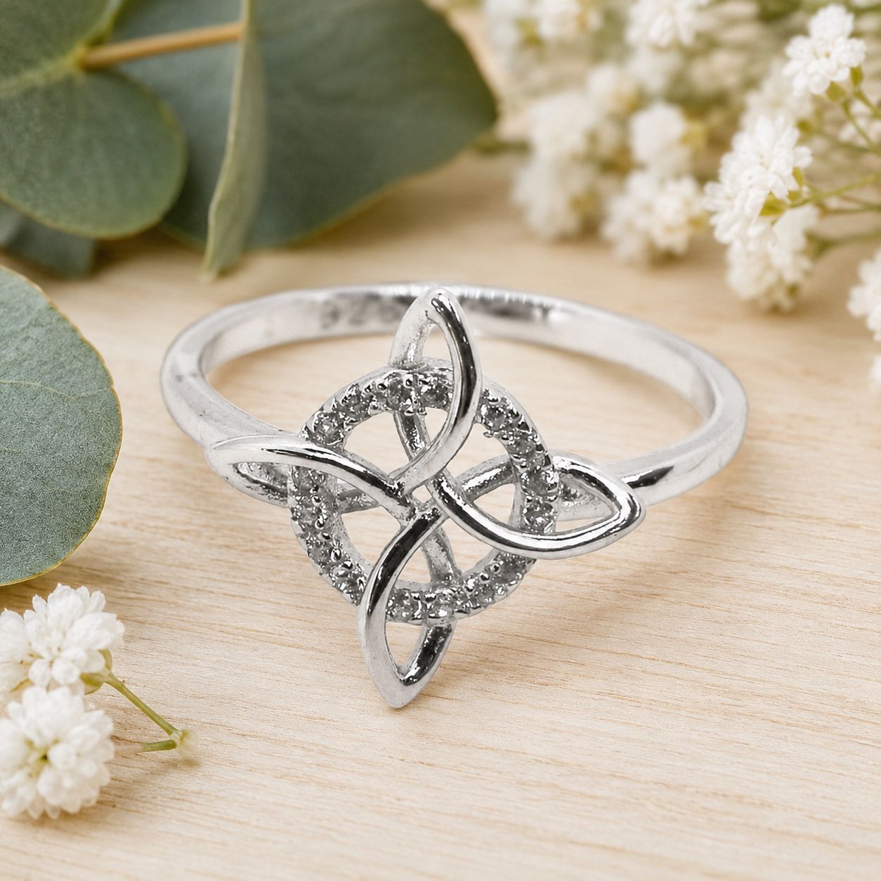 925 sterling silver Witch’s Knot ring with sparkling clear accents displayed on a light wooden table