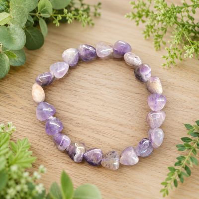 Dream amethyst heart bracelet displayed on a light wooden table with greenery.