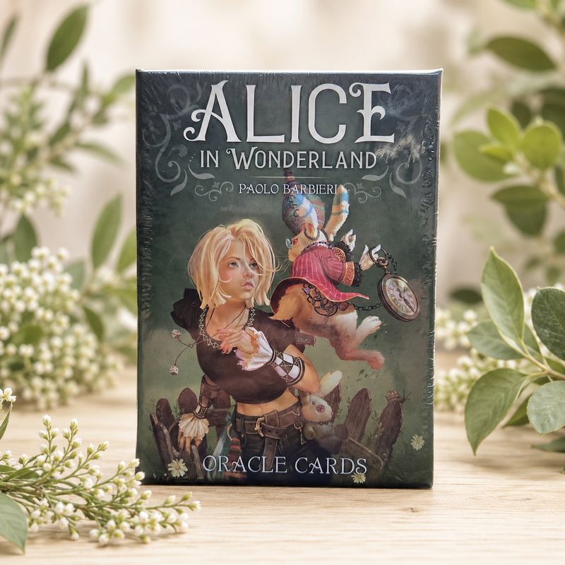 Front of Alice in Wonderland Oracle Cards by Paolo Barbieri displayed on a light wooden table with greenery