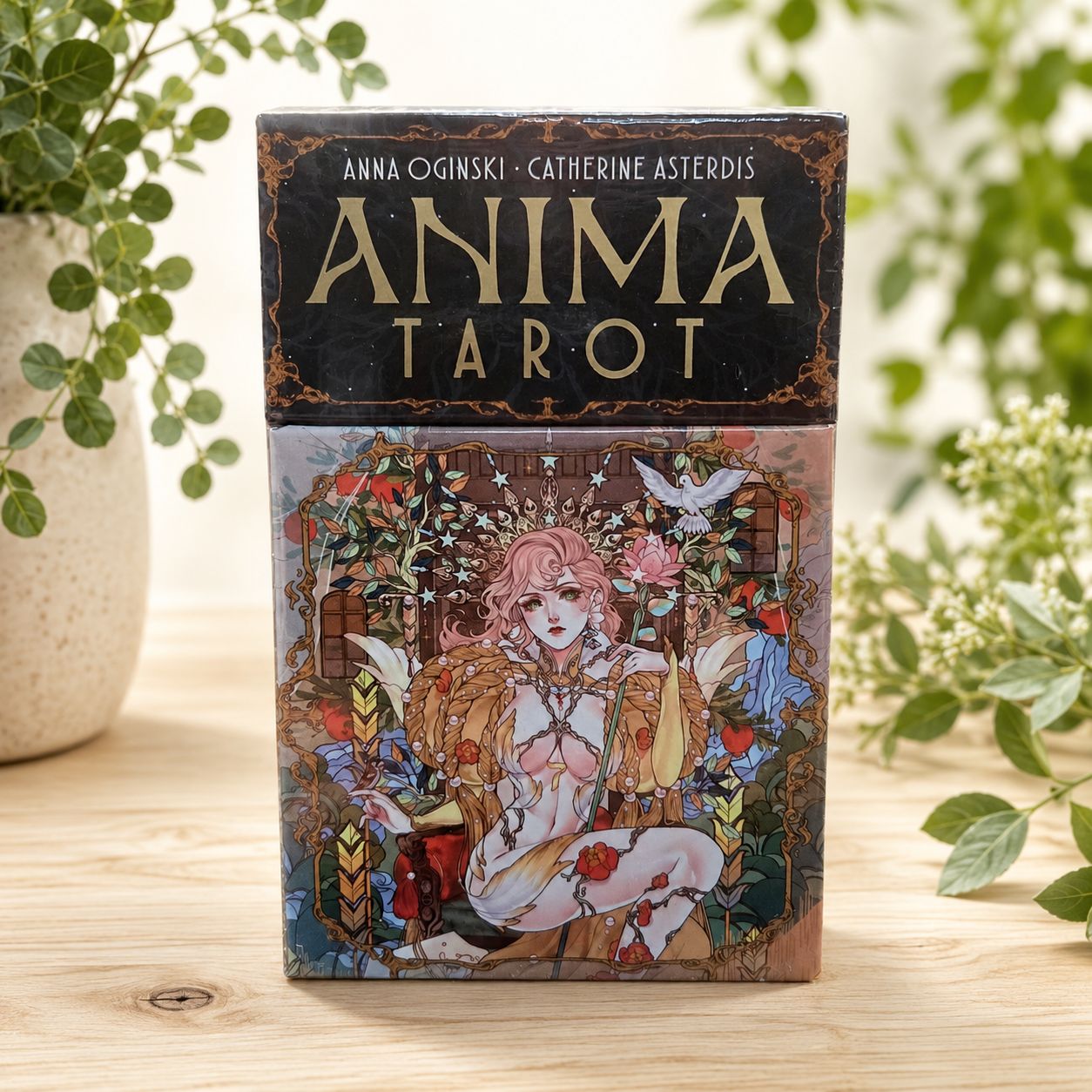 Front of Anima Tarot deck by Anna Oginski with ornate floral artwork displayed on a light wooden table