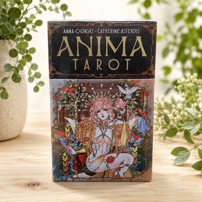 Front of Anima Tarot deck by Anna Oginski with ornate floral artwork displayed on a light wooden table