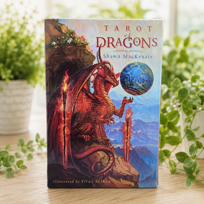 Front of Tarot of Dragons deck by Shawn MacKenzie with red dragon artwork on a light wooden table