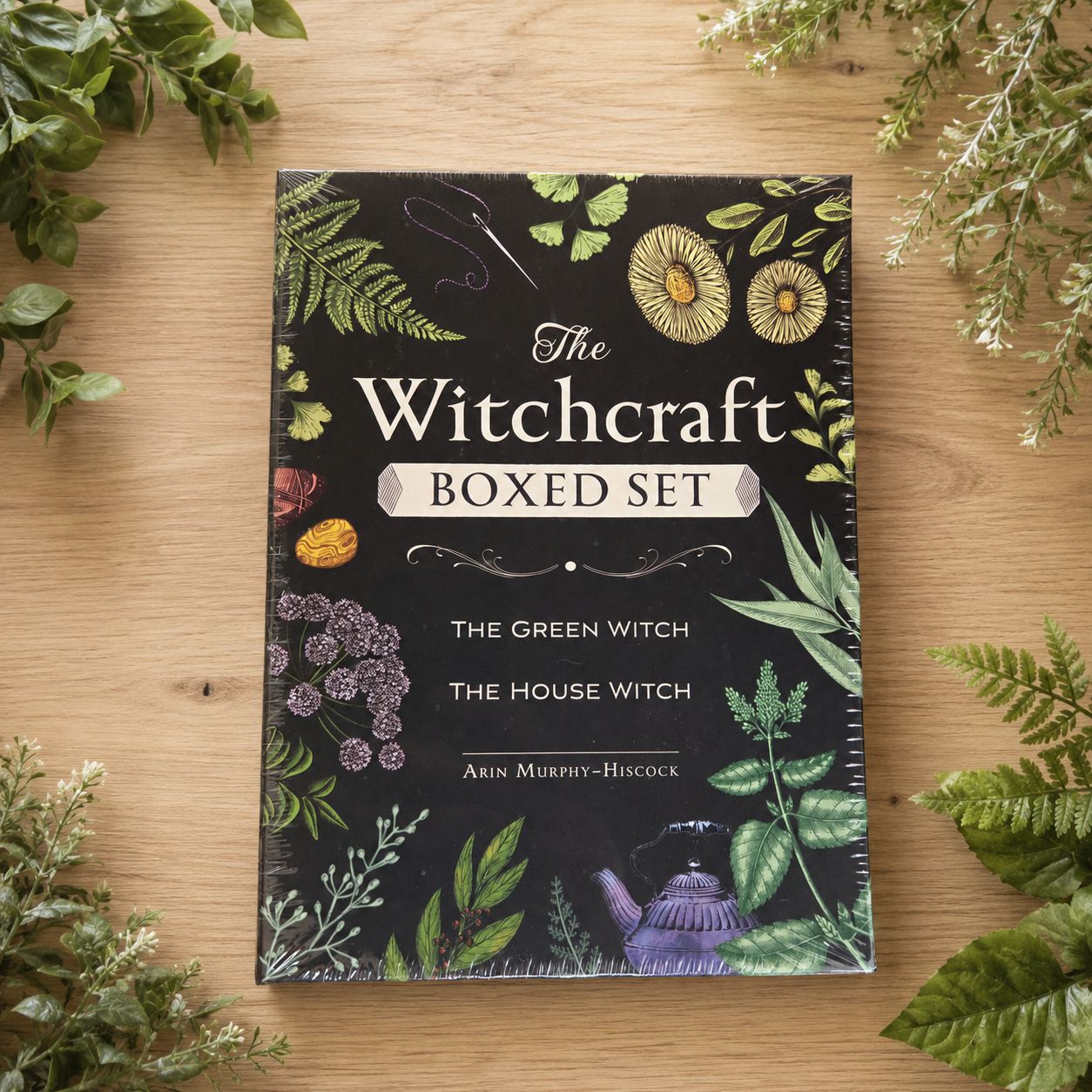The Witchcraft Boxed Set with The Green Witch and The House Witch displayed on light wood with greenery.