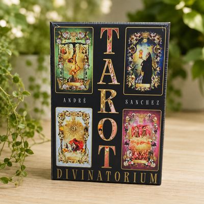 Front of Tarot Divinatorium by André Sanchez displayed on a light wooden table with greenery.