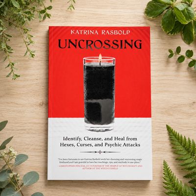Uncrossing by Katrina Rasbold displayed on a light wooden table with greenery.