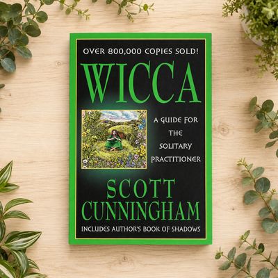 Wicca by Scott Cunningham displayed on a light wooden table with greenery.
