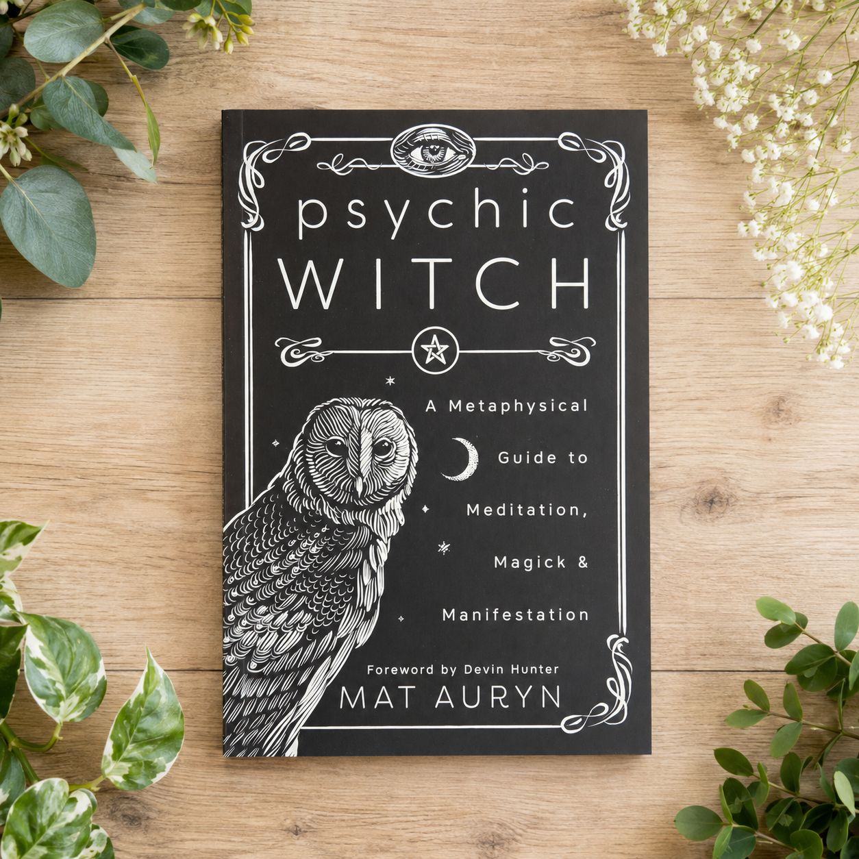Psychic Witch by Mat Auryn displayed on a light wooden table with greenery.