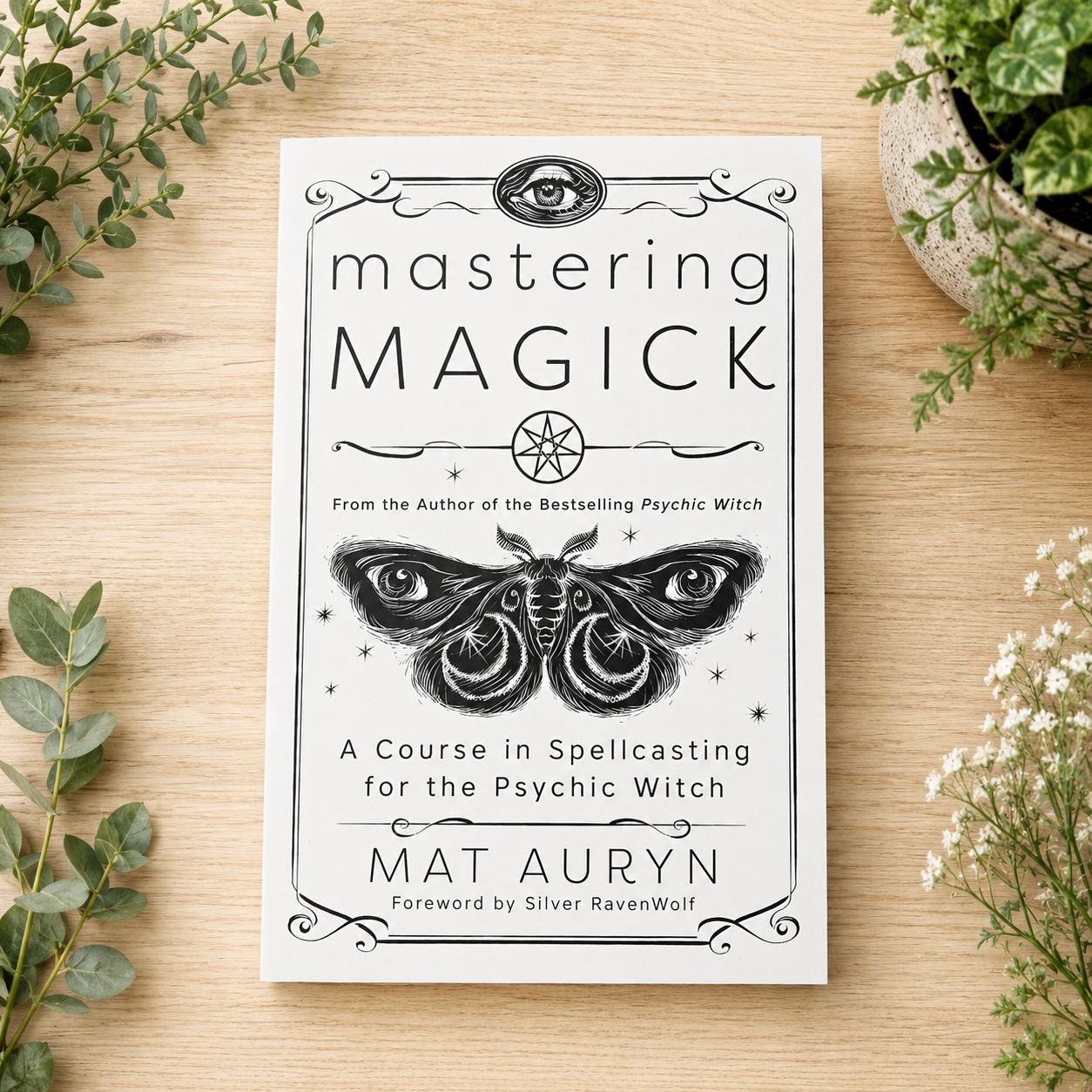 Mastering Magick by Mat Auryn displayed on a light wooden table with greenery.