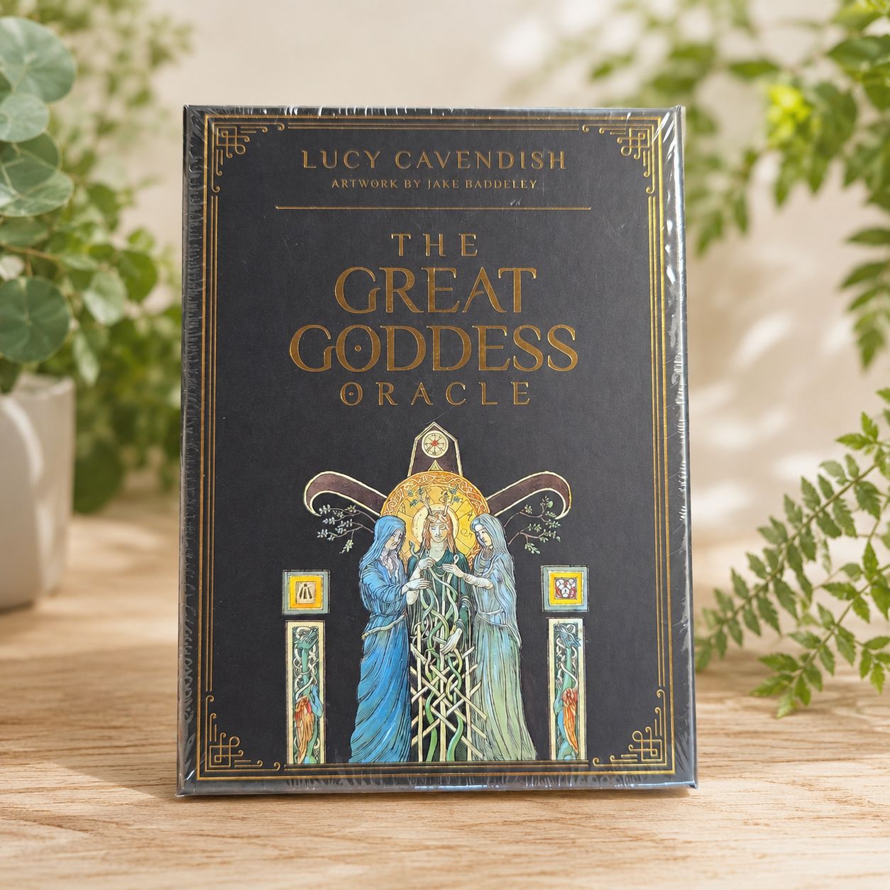 The Great Goddess Oracle by Lucy Cavendish displayed on a light wooden table with greenery.