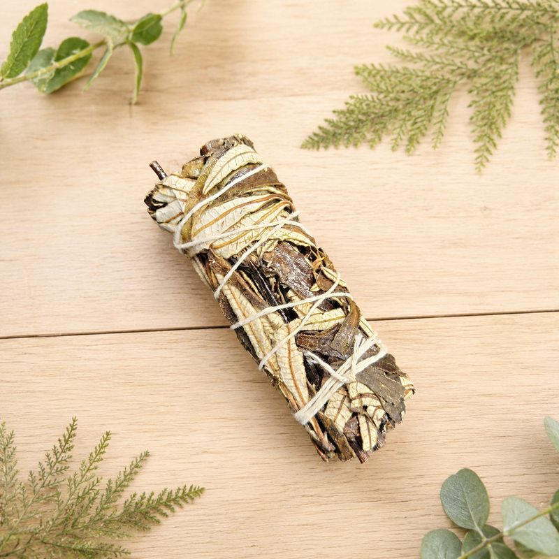 Yerba Santa smudge stick on a light wooden table with greenery