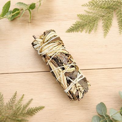 Yerba Santa smudge stick on a light wooden table with greenery