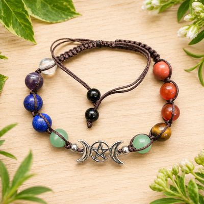 Triple Moon Pentagram chakra adjustable bracelet on a light wooden table with greenery.