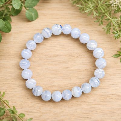 Blue Lace Agate 8mm bead bracelet displayed on a light wooden table with greenery.