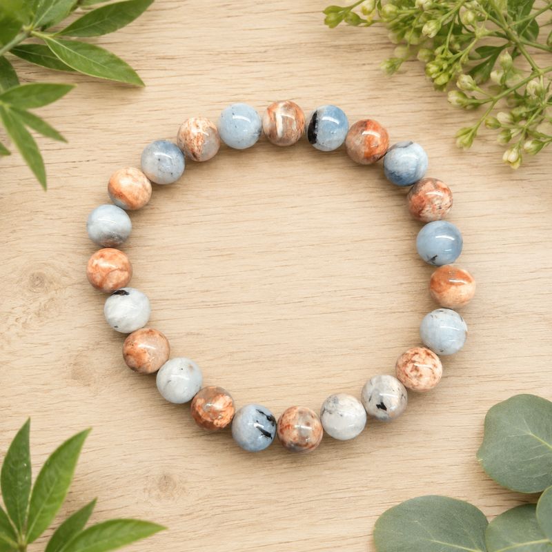 Island Aquamarine 8mm gemstone bracelet on a light wooden table with greenery.