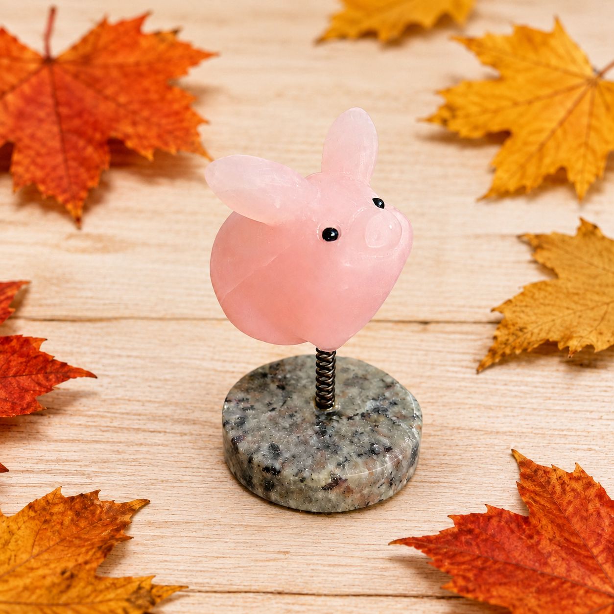 Rose Quartz pig on Yooperlite base displayed on a light wooden table with autumn leaves