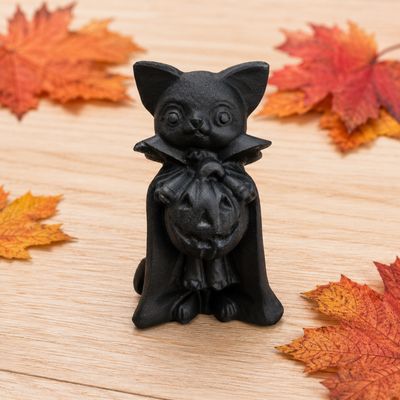 Obsidian cat pumpkin carving displayed on a light wooden table with autumn leaves