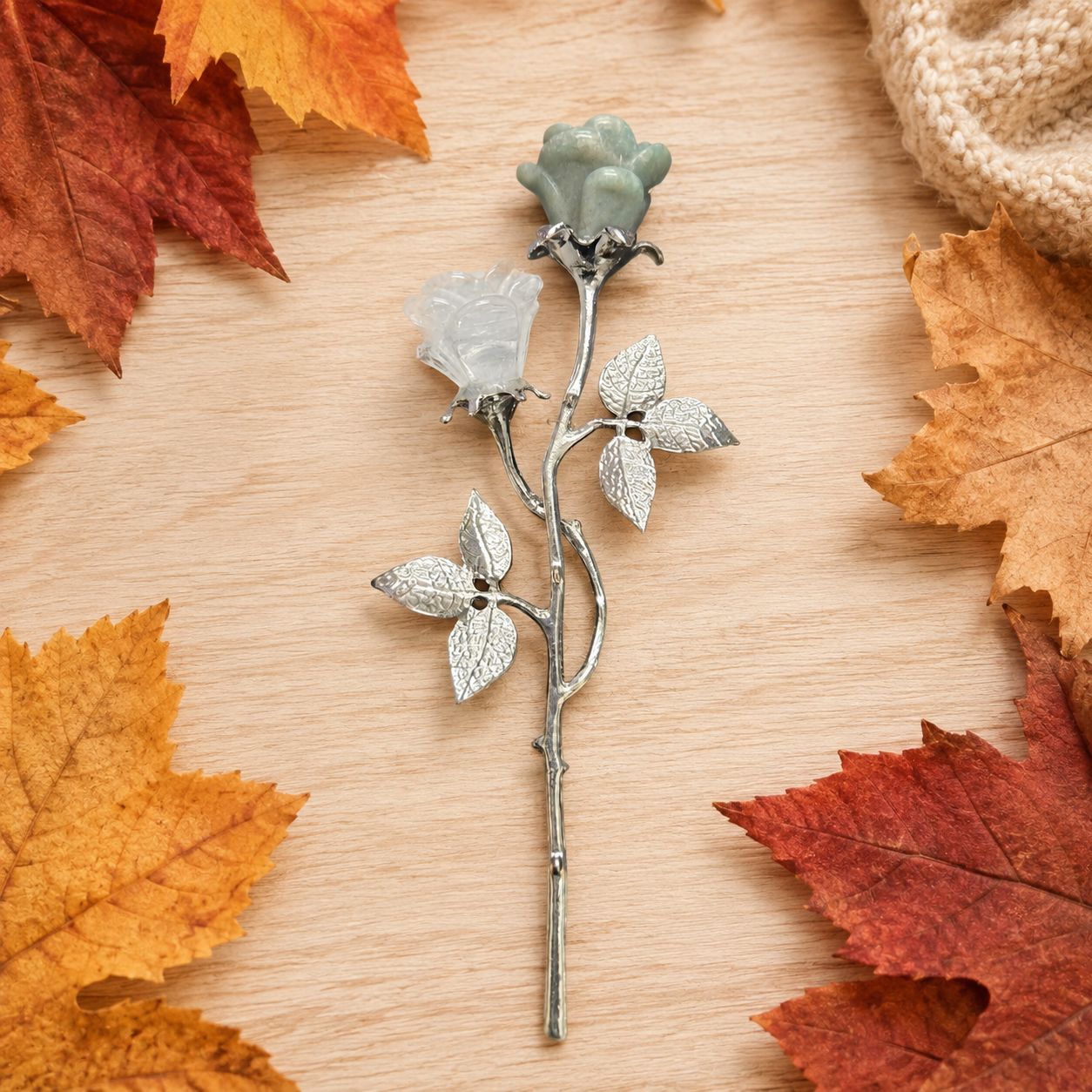 Quartz and Amazonite rose pair on silver-tone stems with textured leaves on a light wooden table