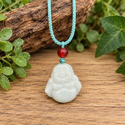 Jade Buddha pendant necklace with green adjustable woven cord and red accent bead displayed on natural wood.