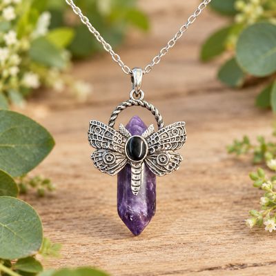 Amethyst dragonfly point necklace with silver-tone pendant and stainless steel chain on light wood with greenery.