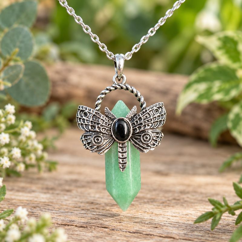 Green aventurine dragonfly point necklace with silver-tone pendant and stainless steel chain on light wood with greenery.