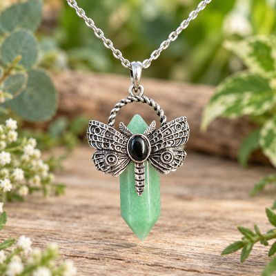 Green aventurine dragonfly point necklace with silver-tone pendant and stainless steel chain on light wood with greenery.