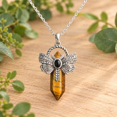 Tiger eye dragonfly point necklace with silver-tone pendant and stainless steel chain on light wood with greenery.