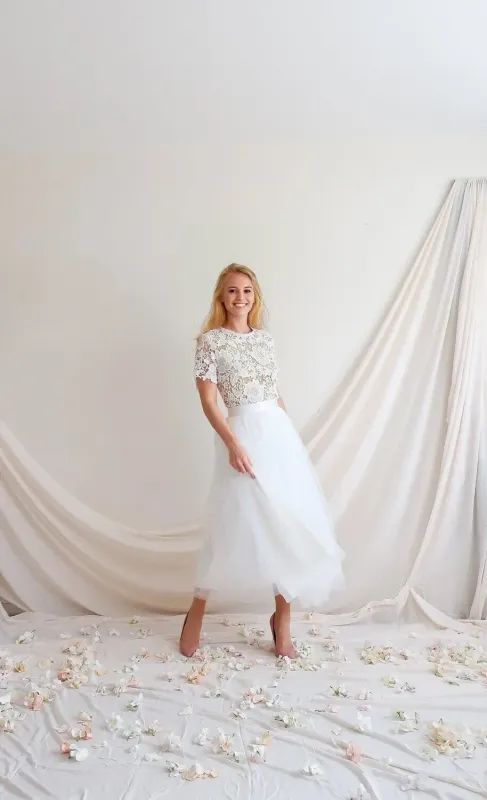 Robe de Mariée Mi-Longue en Dentelle avec Dos Nu Éclatant - VALENTINA DOS NU INVERSE Robe de mariée mi-longue VALENTINA en dentelle avec dos nu inversé, portée dans un décor de mariage, Faith Cauvain