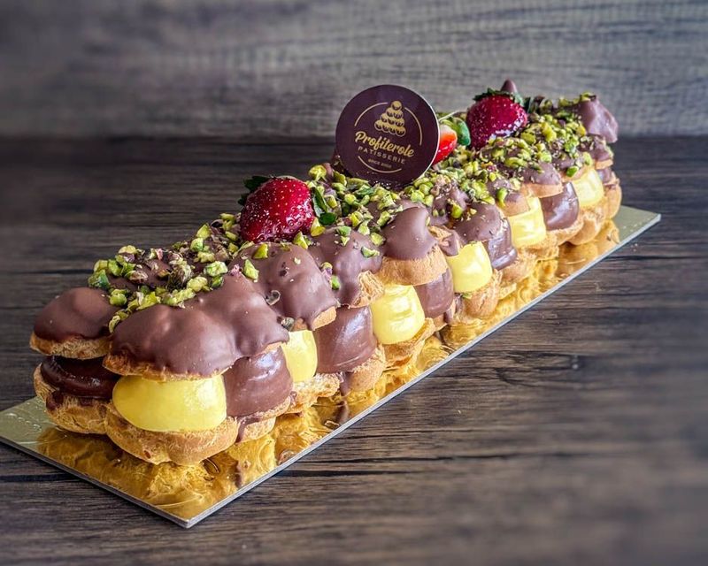 a profiterole log cake with vanilla and chocolate custard in the middle and pistachio on top