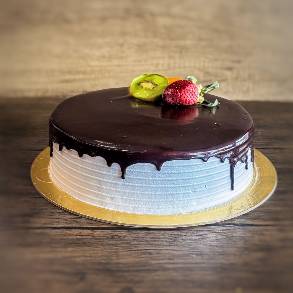 a round ice cream cake with chocolate sauce on top, decorated with a strawberry and kiwi