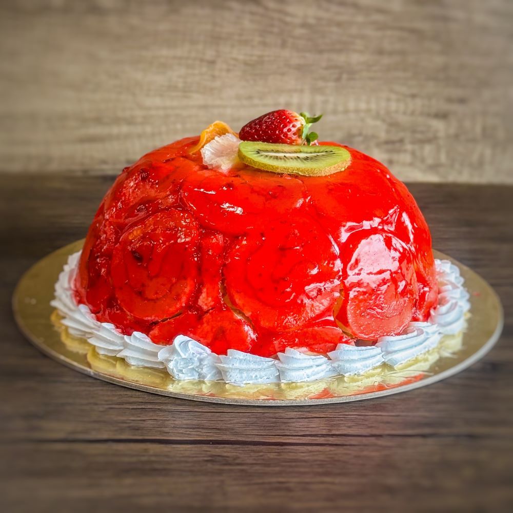 a Swiss roll ice cream cake covered in strawberry sauce, fresh strawberries and kiwis on top.