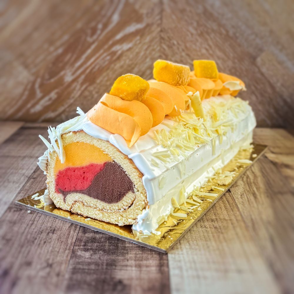 an ice cream cake with strawberry, mango and chocolate ice cream covered by vanilla sponge, topped with mango cream