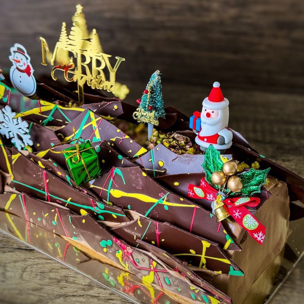 a Christmas Log Cake - Dubai filling and chocolate ganaches decorations, topping with various xmas figure decorations