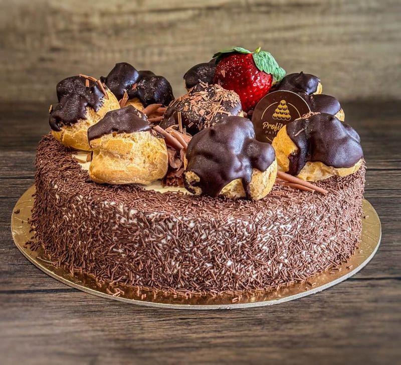 A chocolate profiterole cake with 7 profiteroles on top