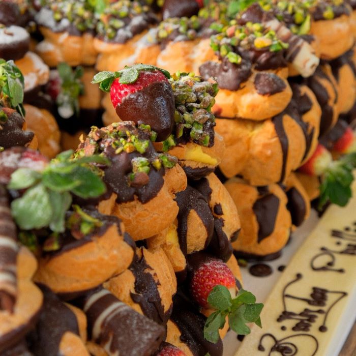 profiterole double letters cake with pistachio and strawberries on top