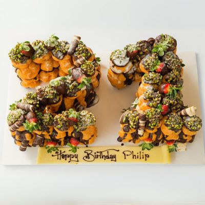 profiterole number-shaped cake with pistachio and strawberries on top