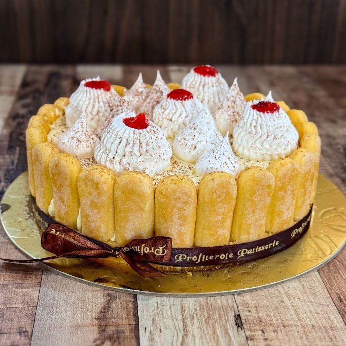 A fraisier cake with surrounded lady fingers side view