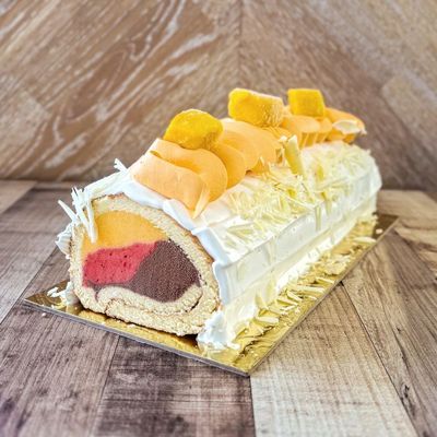an ice cream cake with strawberry, mango and chocolate ice cream covered by vanilla sponge, topped with mango cream
