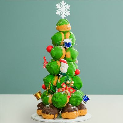 A christmas tree cake made from Profiteroles towering into a green cake with a white snowflake as the star