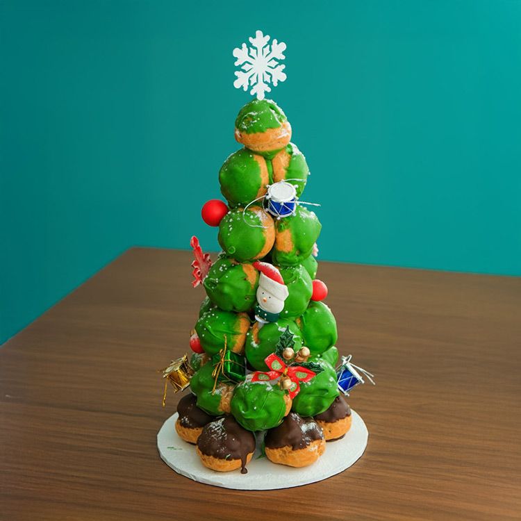 A green Christmas tree cake made from Profiteroles towering with a white snowflake as the star
