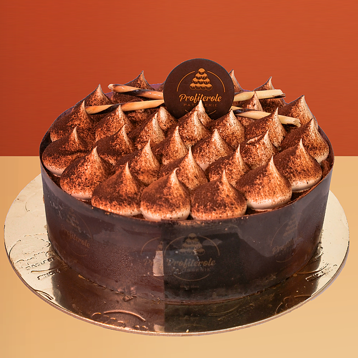 Tiramisu cake with dark chocolate sides and peaked cocoa-dusted mascarpone cream dollops on top by Profiterole Patisserie