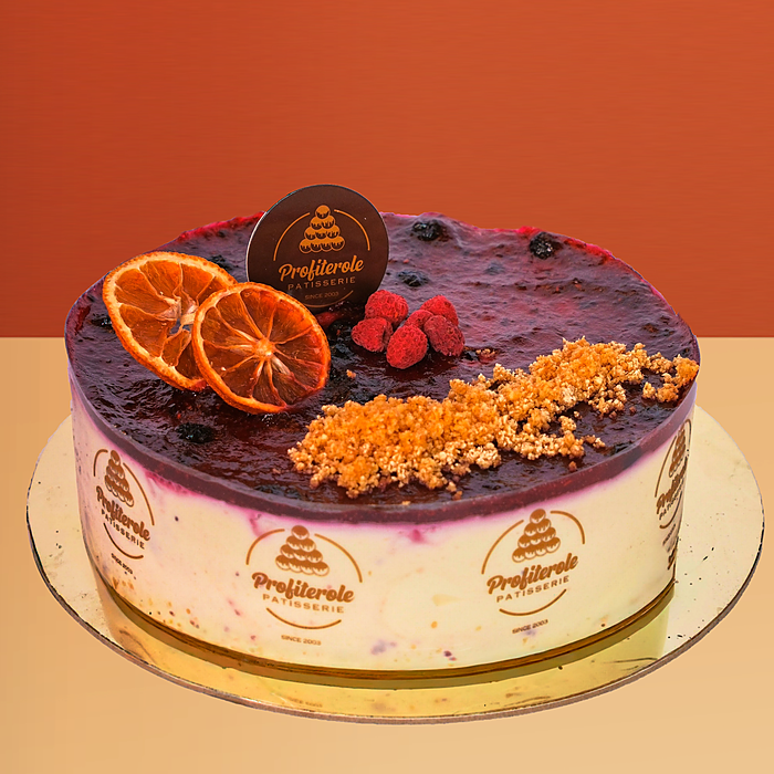 Blueberry cheesecake with berry compote a dried orange slice fresh raspberries and crumble topping by Profiterole Patisserie