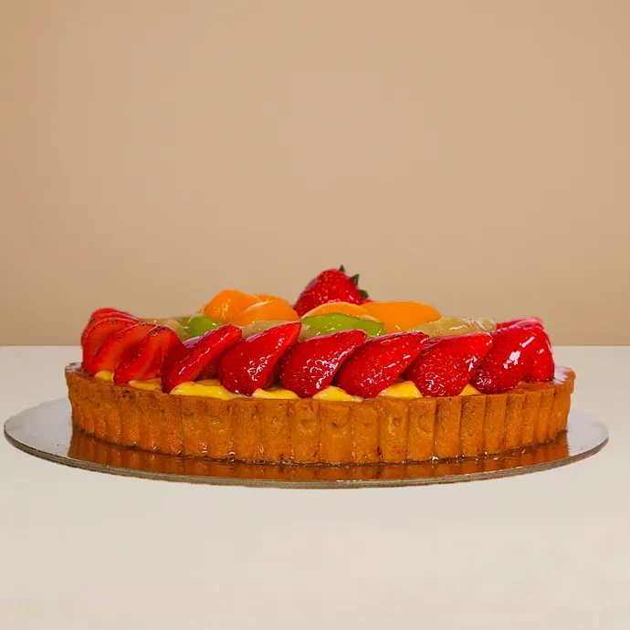 side view of the round fruit cake showing the nice ridges of its shortbread pastry base and strawberry toppings
