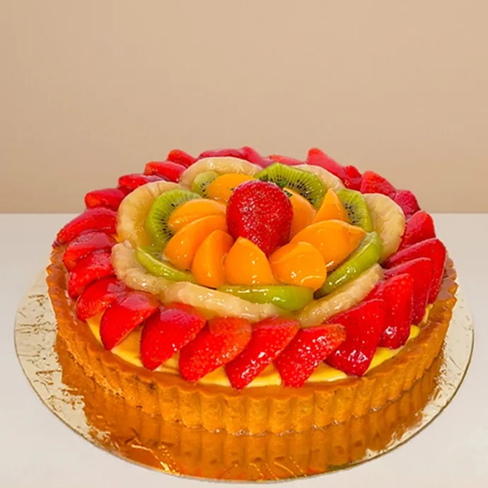 side view of the round fruit cake showing the nice ridges of its shortbread pastry base and strawberry toppings