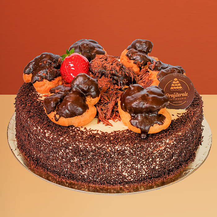 Chocolate profiterole cake covered in chocolate sprinkles with chocolate-dipped profiteroles and a fresh strawberry on top 