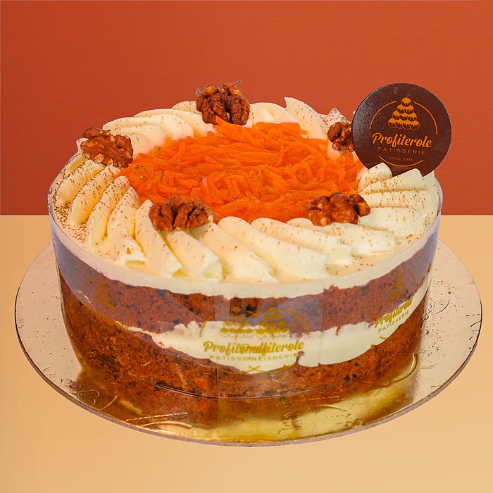 Carrot cake with semi-naked cream frosting showing sponge layers topped with shredded carrot walnuts and cream by Profiterole