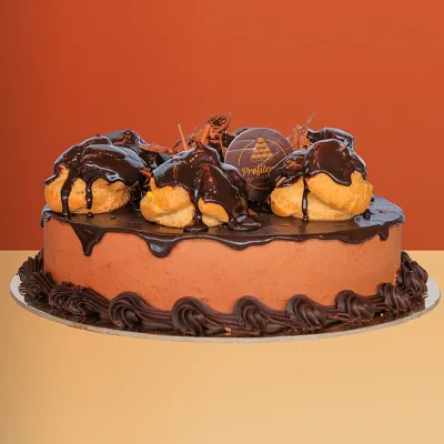 Chocolate mousse profiterole cake topped with profiteroles, chocolate ganache & piped chocolate border by Profiterole