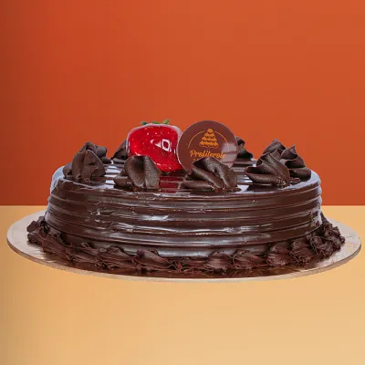 Chocolate Mud Cake Chocolate mud cake with glossy chocolate ganache a chocolate bar piece and cocoa truffles on top by Profiterole Patisserie