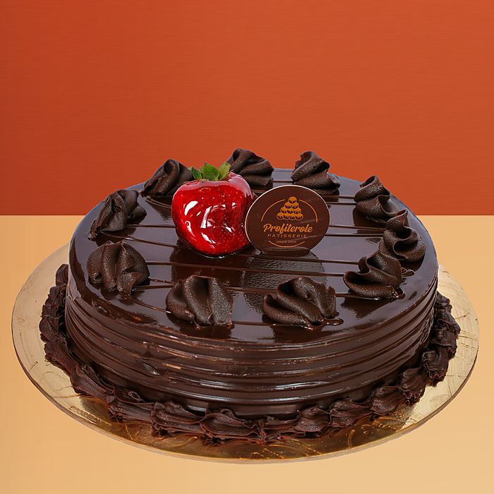 Chocolate mud cake with glossy chocolate ganache a chocolate bar piece and cocoa truffles on top by Profiterole Patisserie