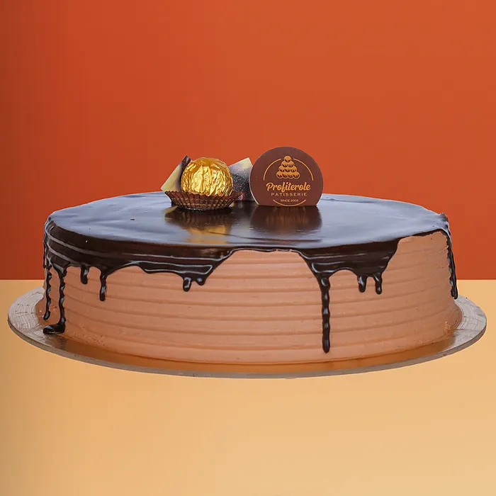 Ferrero Rocher cake with rich chocolate ganache drip and a golden Ferrero Rocher ball on top by Profiterole Patisserie