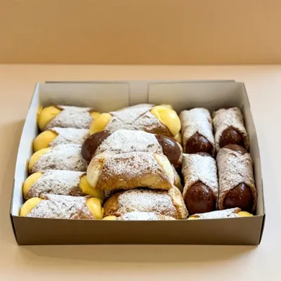 a box of cannolis with assorted flavours like chocolate, vanilla, and ricotta